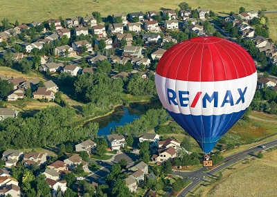 RE/MAX balloon over green grass houses and lake