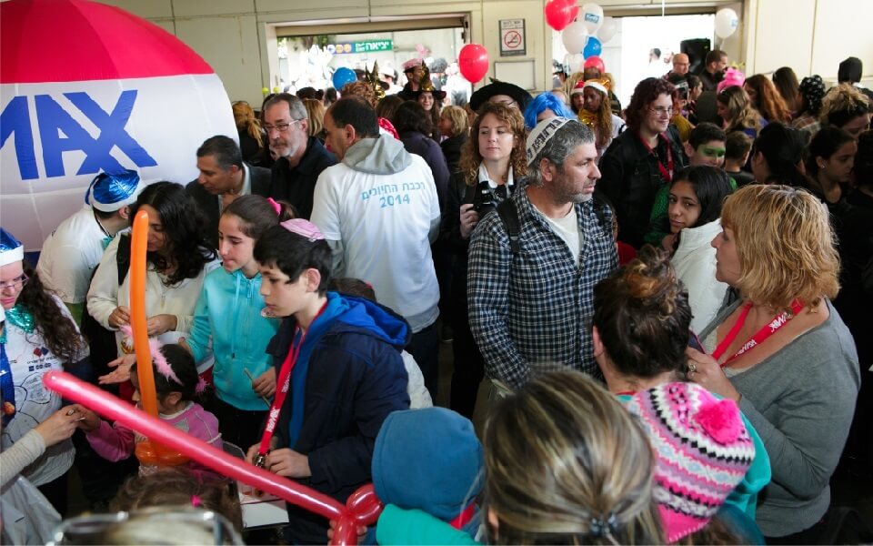 People and children at an event with a RE/MAX balloon and balloons